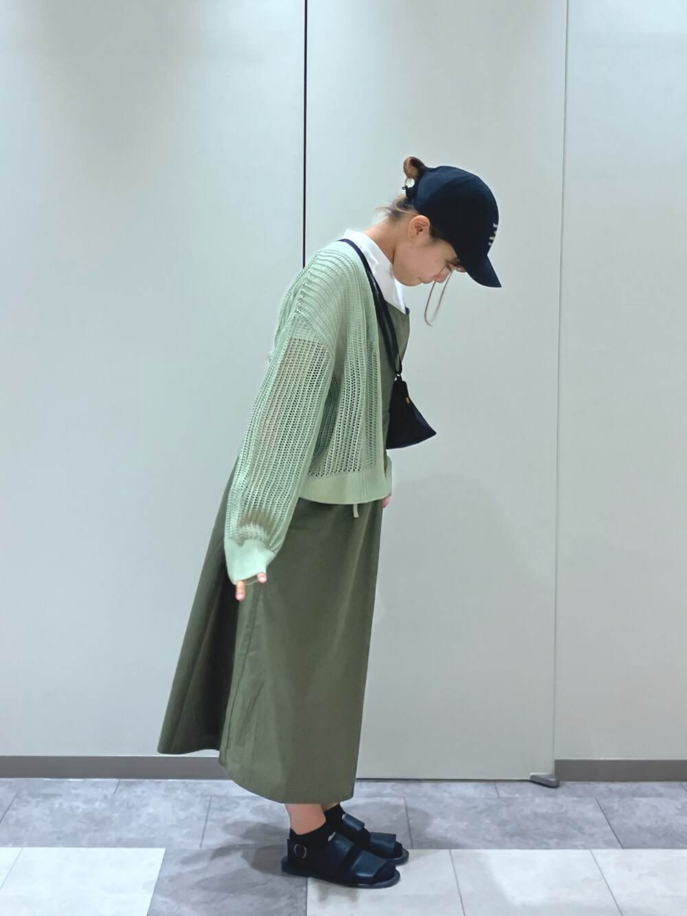 ブラック系のサンダル、グリーン系のワンピース、ブラック系のハンドバッグを着用したレディースの春コーディネートの4枚目の写真