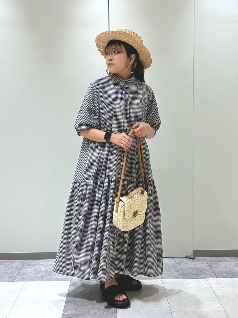 ホワイト系のハンドバッグ、ブラック系のワンピース、ブラック系のサンダルを着用したレディースの夏コーディネートの4枚目の写真