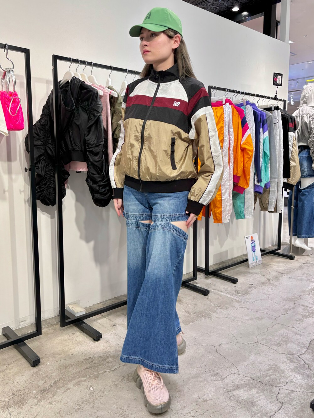 ブラック系のナイロンジャケット、ブルー系のデニムパンツ、グリーン系のキャップを着用したレディースの春コーディネートの2枚目の写真