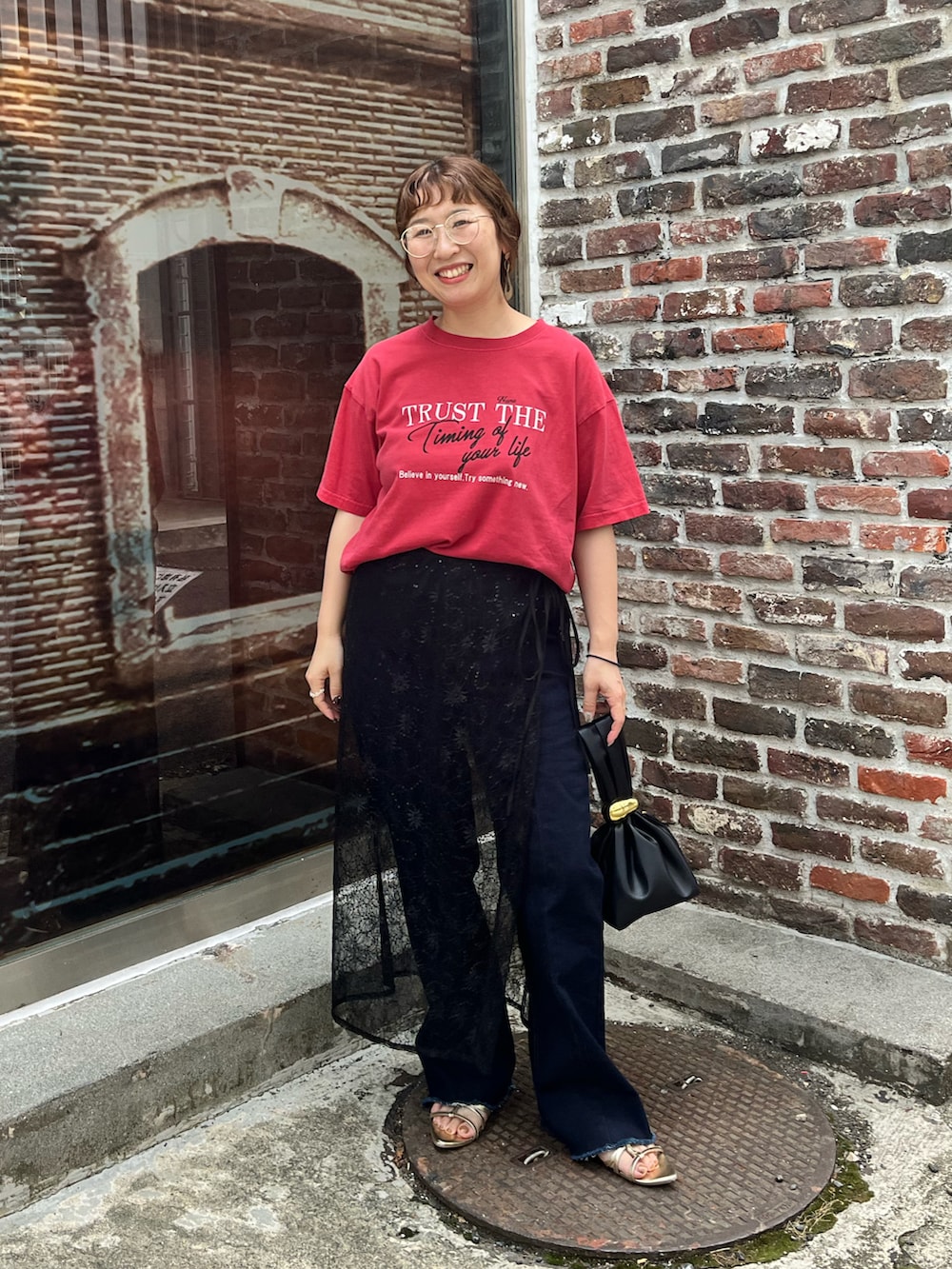 レッド系のTシャツ/カットソー、ブラック系のスカート、ブルー系のデニムパンツを着用したレディースの夏コーディネートの2枚目の写真