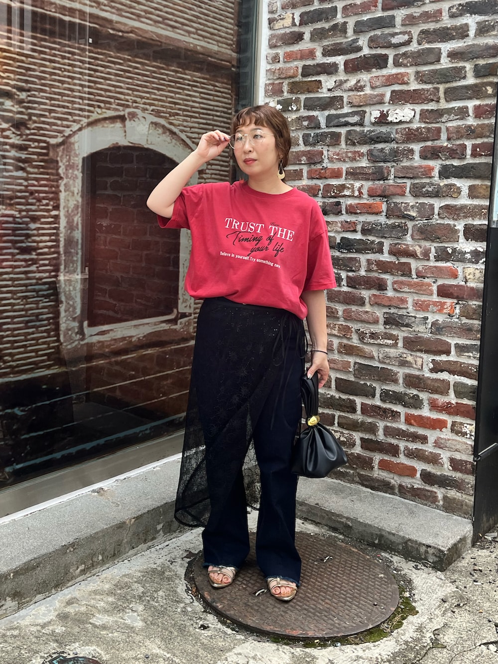 レッド系のTシャツ/カットソー、ブラック系のスカート、ブルー系のデニムパンツを着用したレディースの夏コーディネートの5枚目の写真