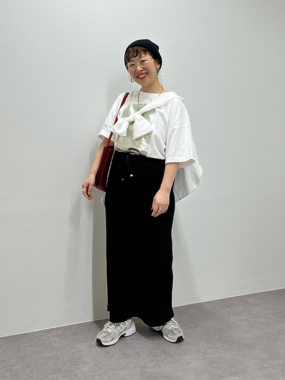 グレー系のスニーカー、ホワイト系のTシャツ/カットソー、ブラック系のスカートを着用したレディースの春コーディネートの3枚目の写真