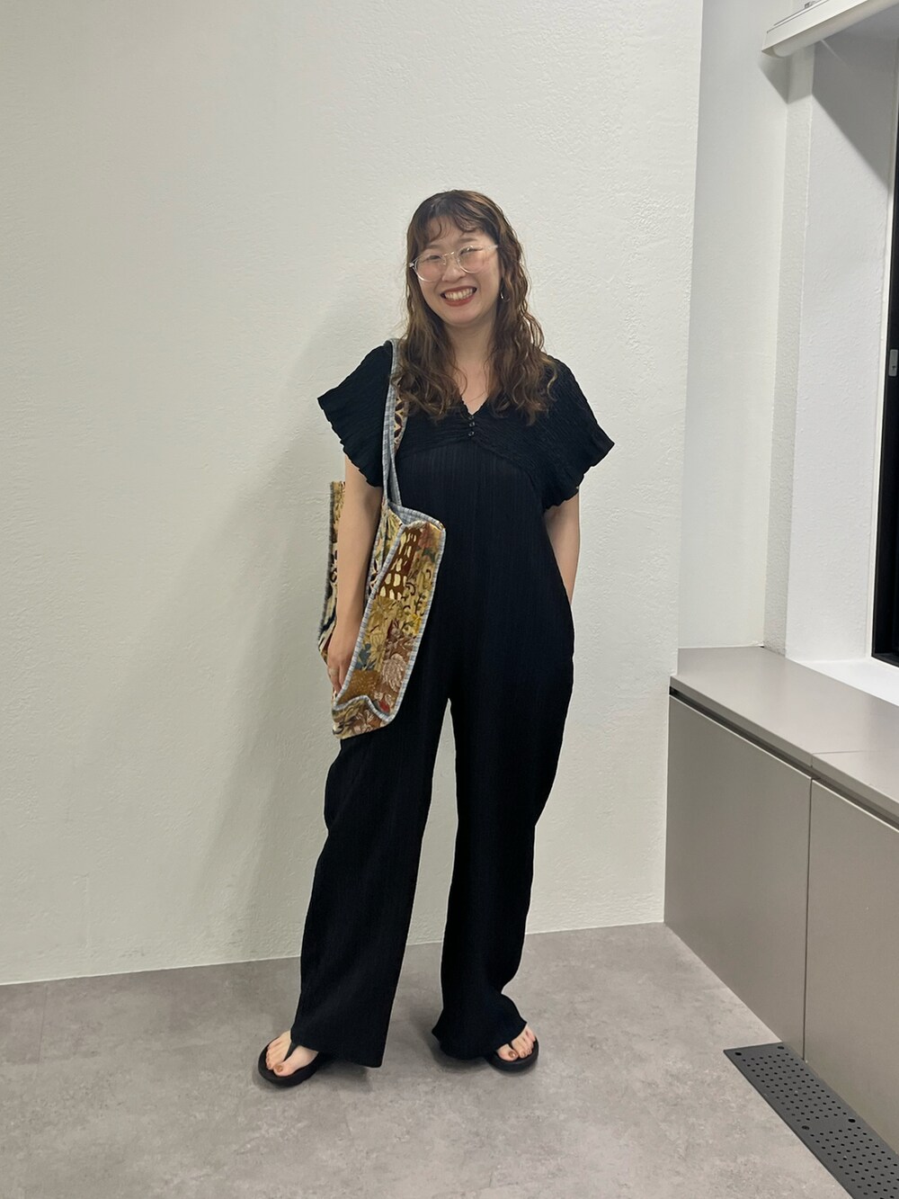 ベージュ系のショルダーバッグ、ブラック系のワンピースを着用したレディースの夏コーディネートの2枚目の写真