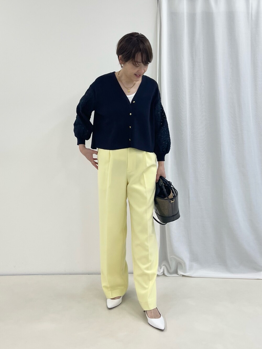 ブルー系のカーディガン/ボレロ、イエロー系のその他パンツ、ブラック系のかごバッグを着用したレディースの春コーディネートの2枚目の写真