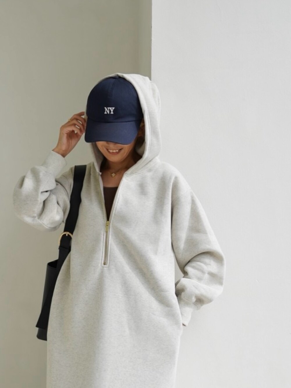 ブラック系のバッグ、ホワイト系のスニーカー、ベージュ系のワンピースを着用したレディースの秋コーディネートの2枚目の写真