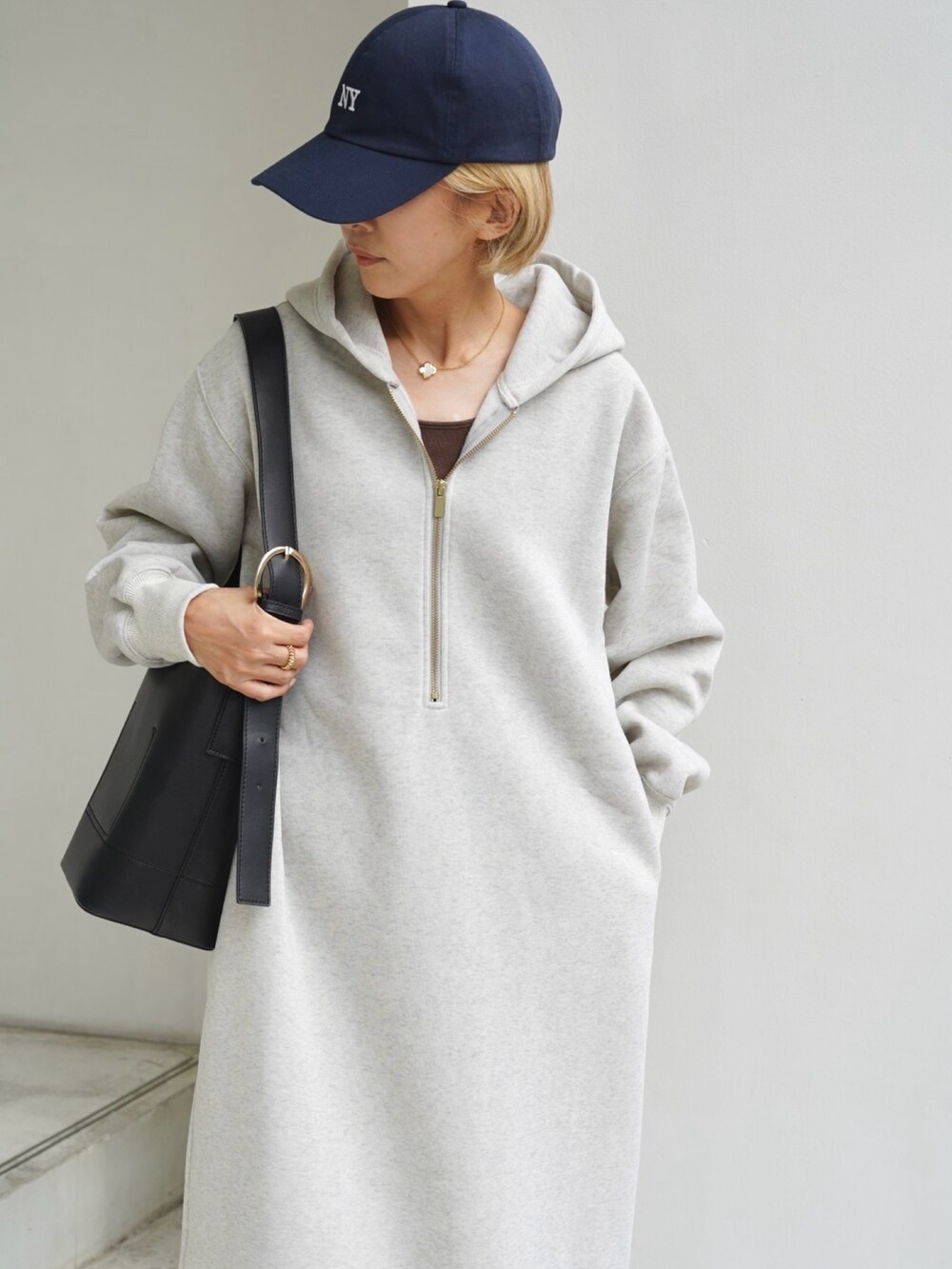 ブラック系のバッグ、ホワイト系のスニーカー、ベージュ系のワンピースを着用したレディースの秋コーディネートの4枚目の写真