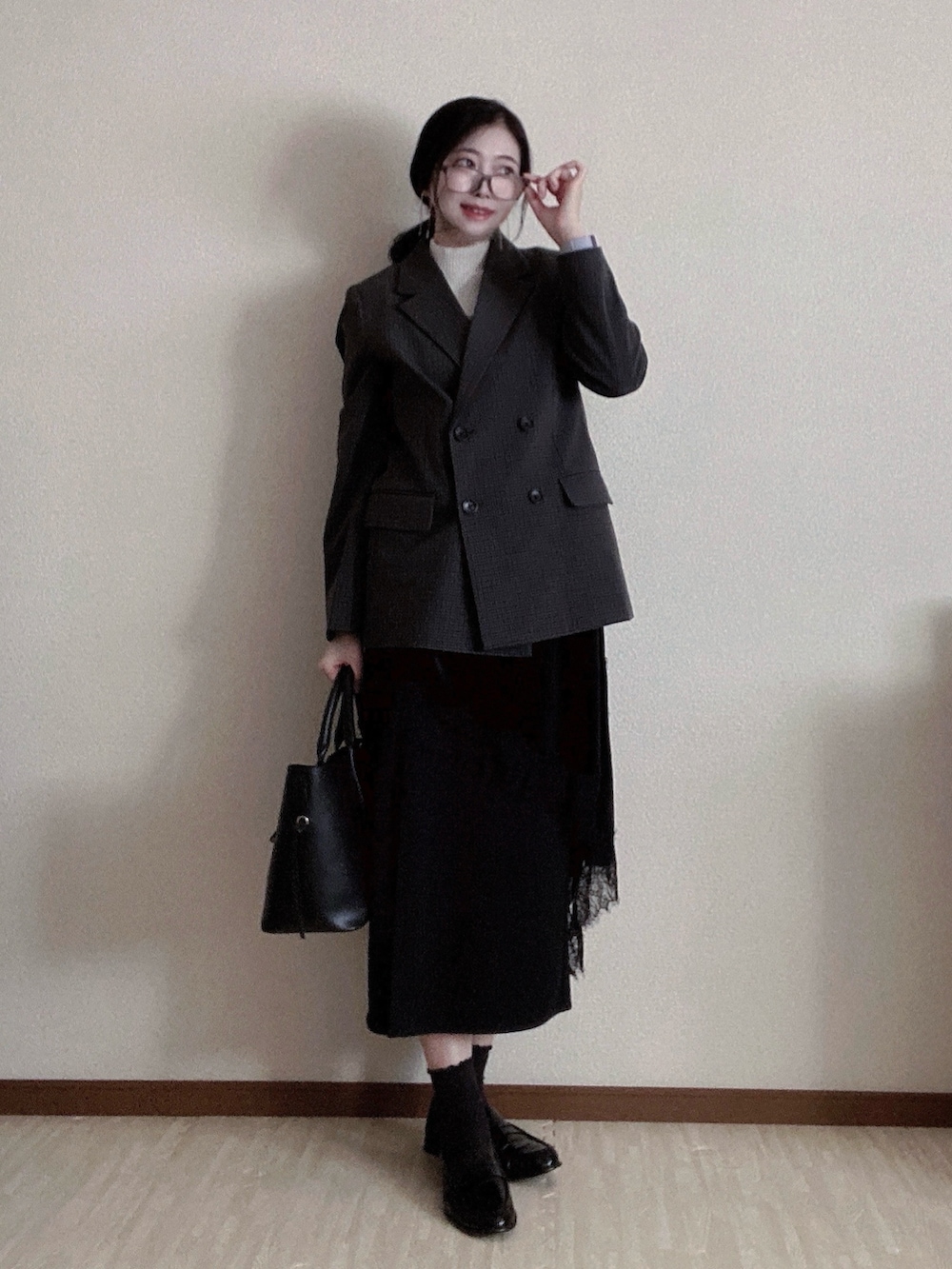 ブラック系のトートバッグ、ホワイト系のトップス、グレー系のジャケット/アウターを着用したレディースの冬コーディネートの2枚目の写真