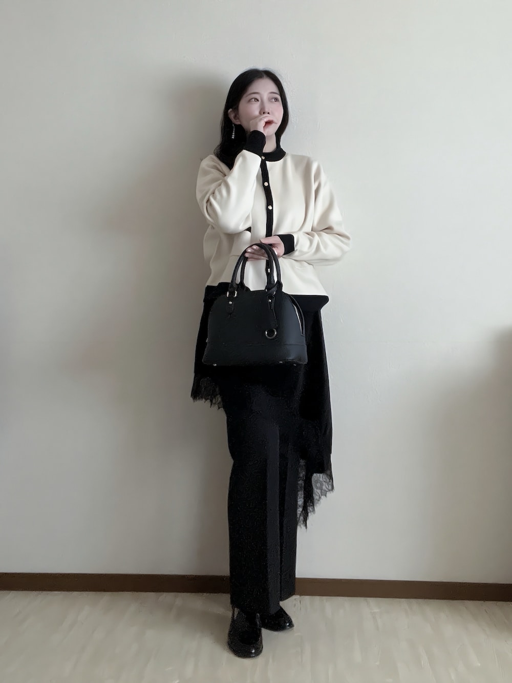 ブラック系のショルダーバッグ、ベージュ系のカーディガン/ボレロ、ブラック系のスラックスを着用したレディースの冬コーディネートの2枚目の写真