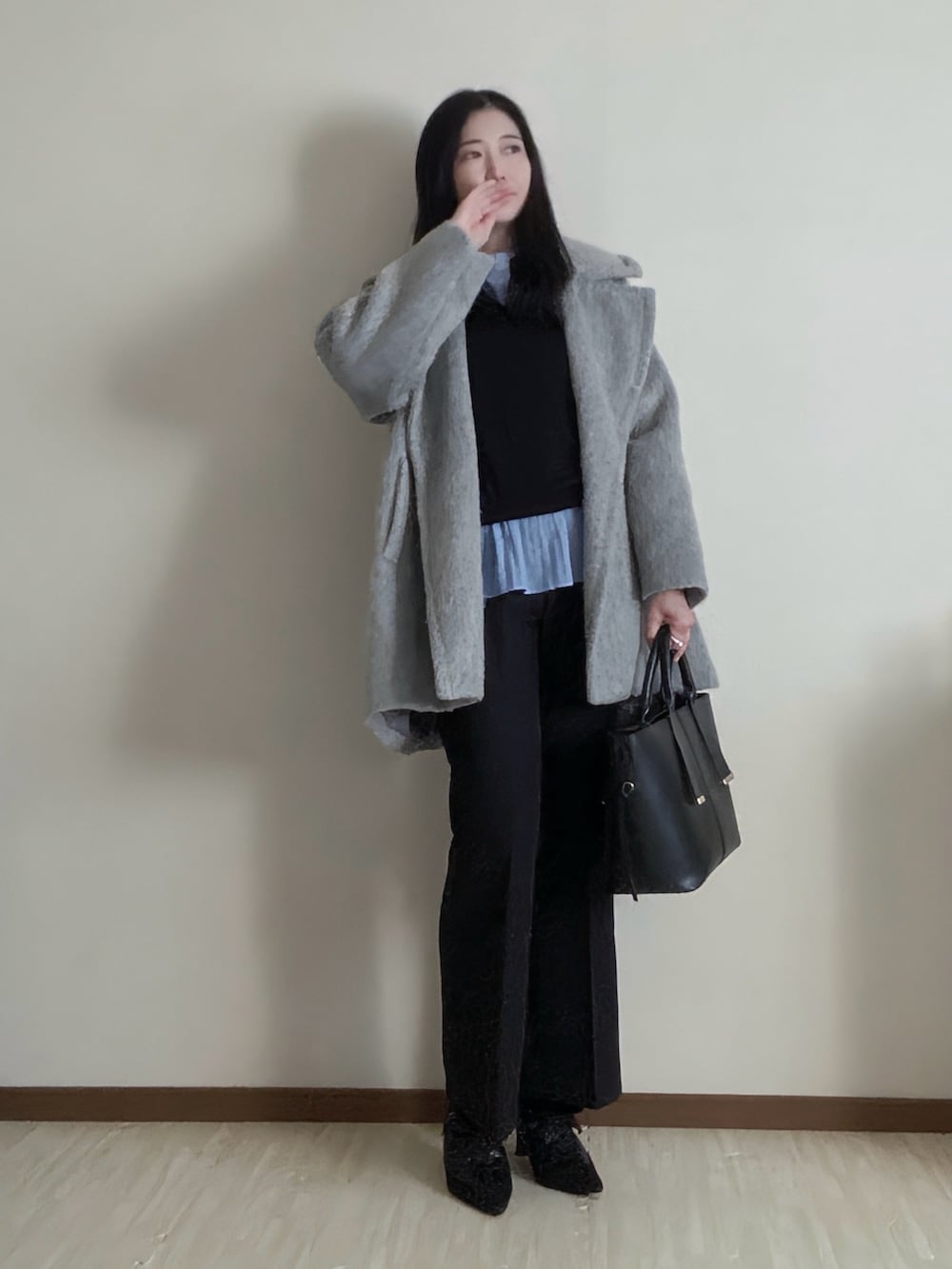 グレー系のピーコート、ブルー系のシャツ/ブラウス、ブラック系のスラックスを着用したレディースの冬コーディネートの3枚目の写真
