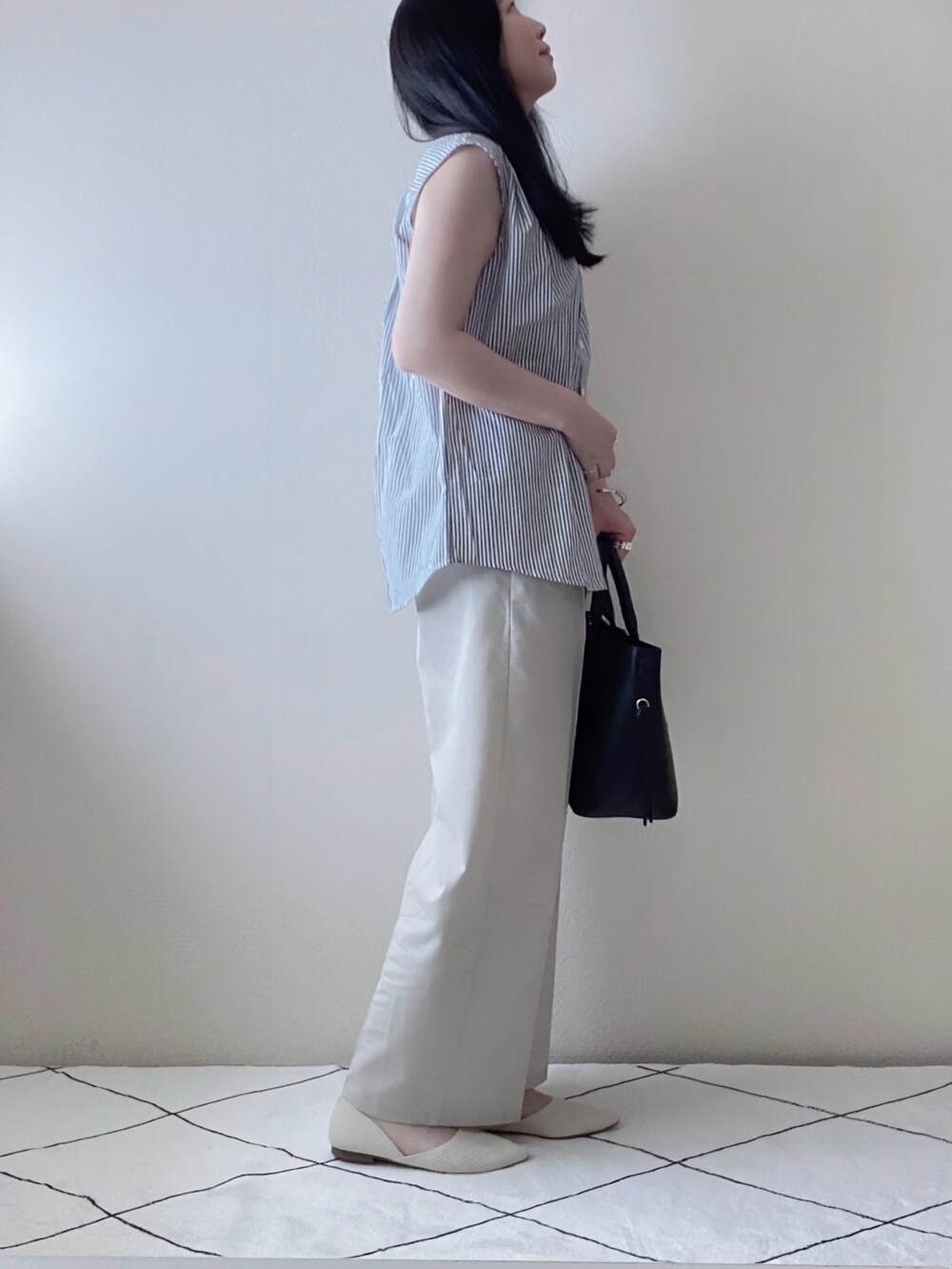 ブラック系のシャツ/ブラウス、ベージュ系のパンツ、ブラック系のトートバッグを着用したレディースの夏コーディネートの2枚目の写真
