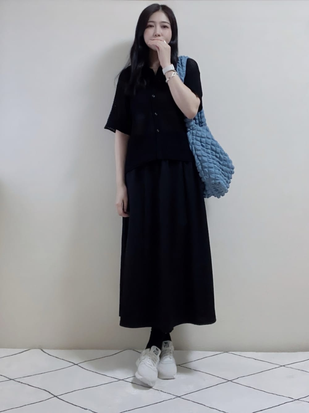 ブラック系のトップス、ブラック系のスカート、ブルー系のショルダーバッグを着用したレディースの春コーディネートの2枚目の写真