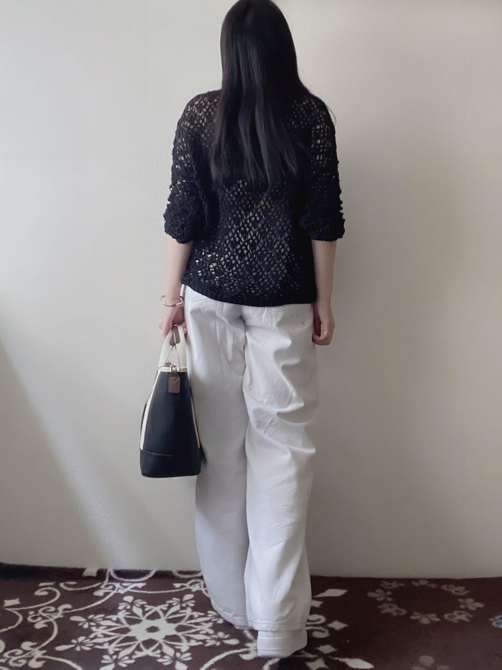 ブラック系のニット/セーター、ホワイト系のパンツ、ブラック系のトートバッグを着用したレディースの春コーディネートの2枚目の写真