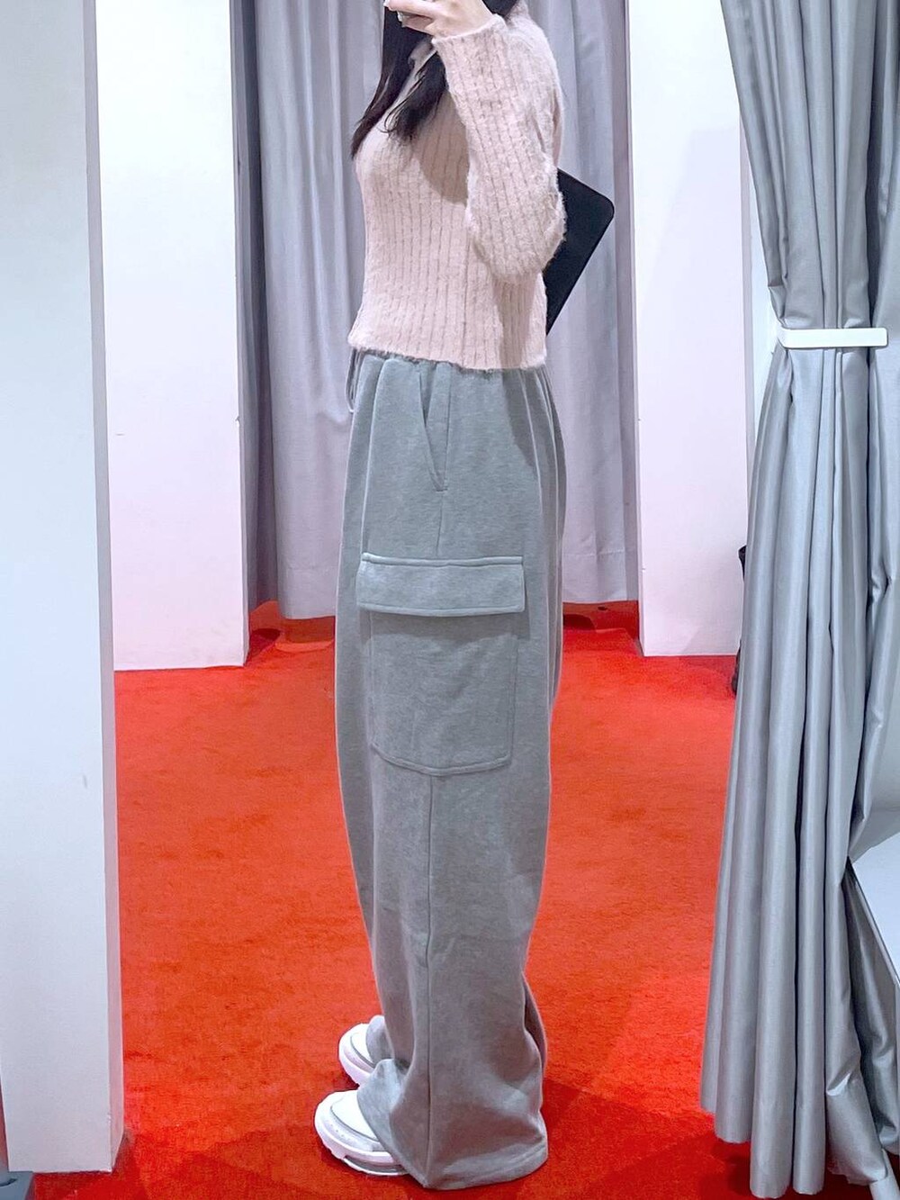 ブラック系のショルダーバッグ、ホワイト系のスニーカー、ピンク系のニット/セーターを着用したレディースの冬コーディネートの2枚目の写真