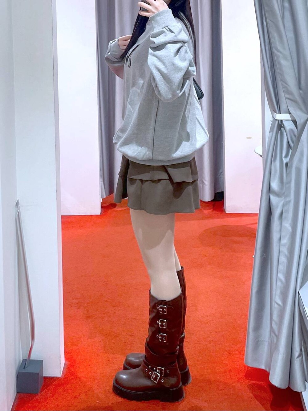 ブラック系のショルダーバッグ、ブラウン系のブーツ、ブラウン系のスカートを着用したレディースの冬コーディネートの2枚目の写真