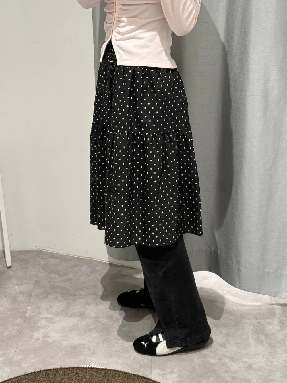 ブラック系のデニムパンツ、ピンク系のカーディガン/ボレロ、ブラック系のスカートを着用したレディースの春コーディネートの2枚目の写真