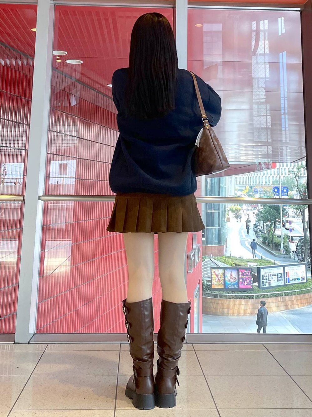 ブラウン系のブーツ、ブルー系のニット/セーター、ブラウン系のハンドバッグを着用したレディースの冬コーディネートの3枚目の写真