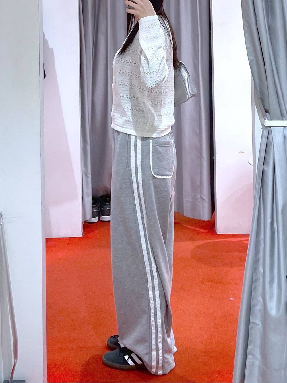 シルバー系のショルダーバッグ、ブラック系のスニーカー、グレー系のスウェットパンツを着用したレディースの冬コーディネートの2枚目の写真