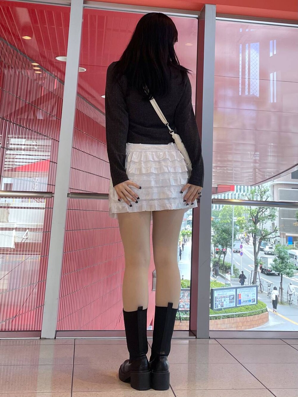 ホワイト系のスカート、ホワイト系のショルダーバッグ、ブラック系のブーツを着用したレディースの秋コーディネートの3枚目の写真