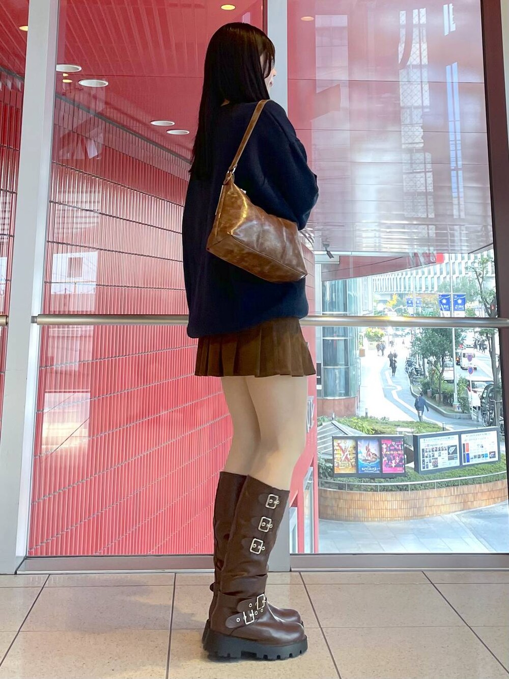 ブラウン系のブーツ、ブルー系のニット/セーター、ブラウン系のハンドバッグを着用したレディースの冬コーディネートの2枚目の写真