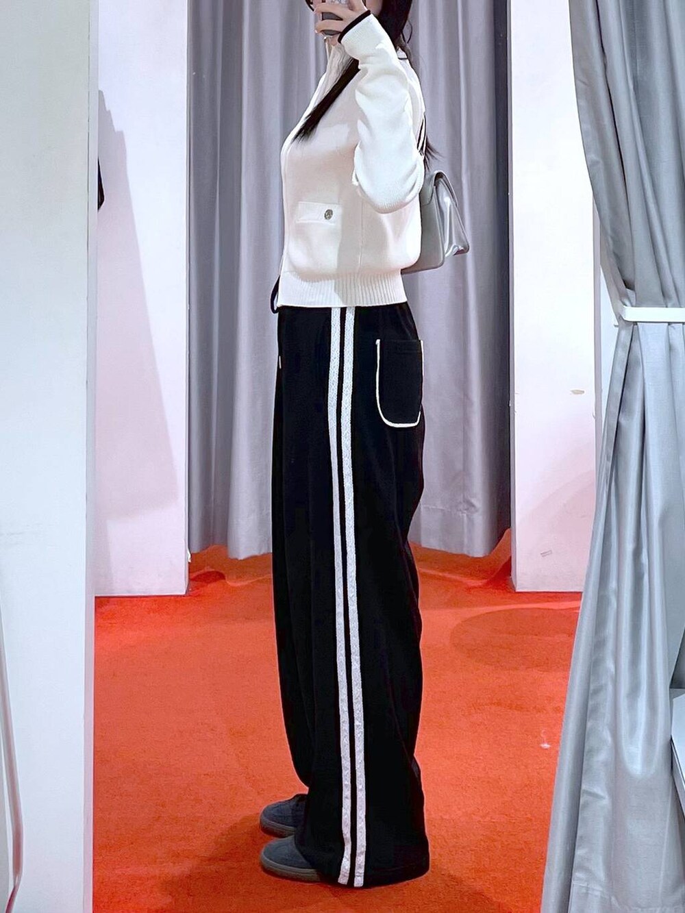 シルバー系のショルダーバッグ、ブラック系のスニーカー、ブラック系のスウェットパンツを着用したレディースの冬コーディネートの2枚目の写真