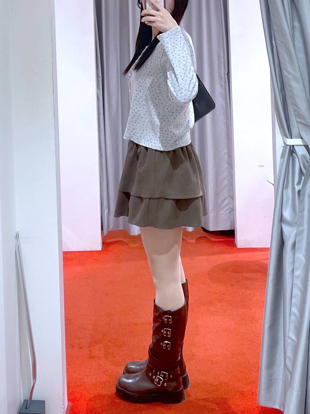 ブラック系のショルダーバッグ、ブラウン系のブーツ、ブラウン系のスカートを着用したレディースの冬コーディネートの2枚目の写真