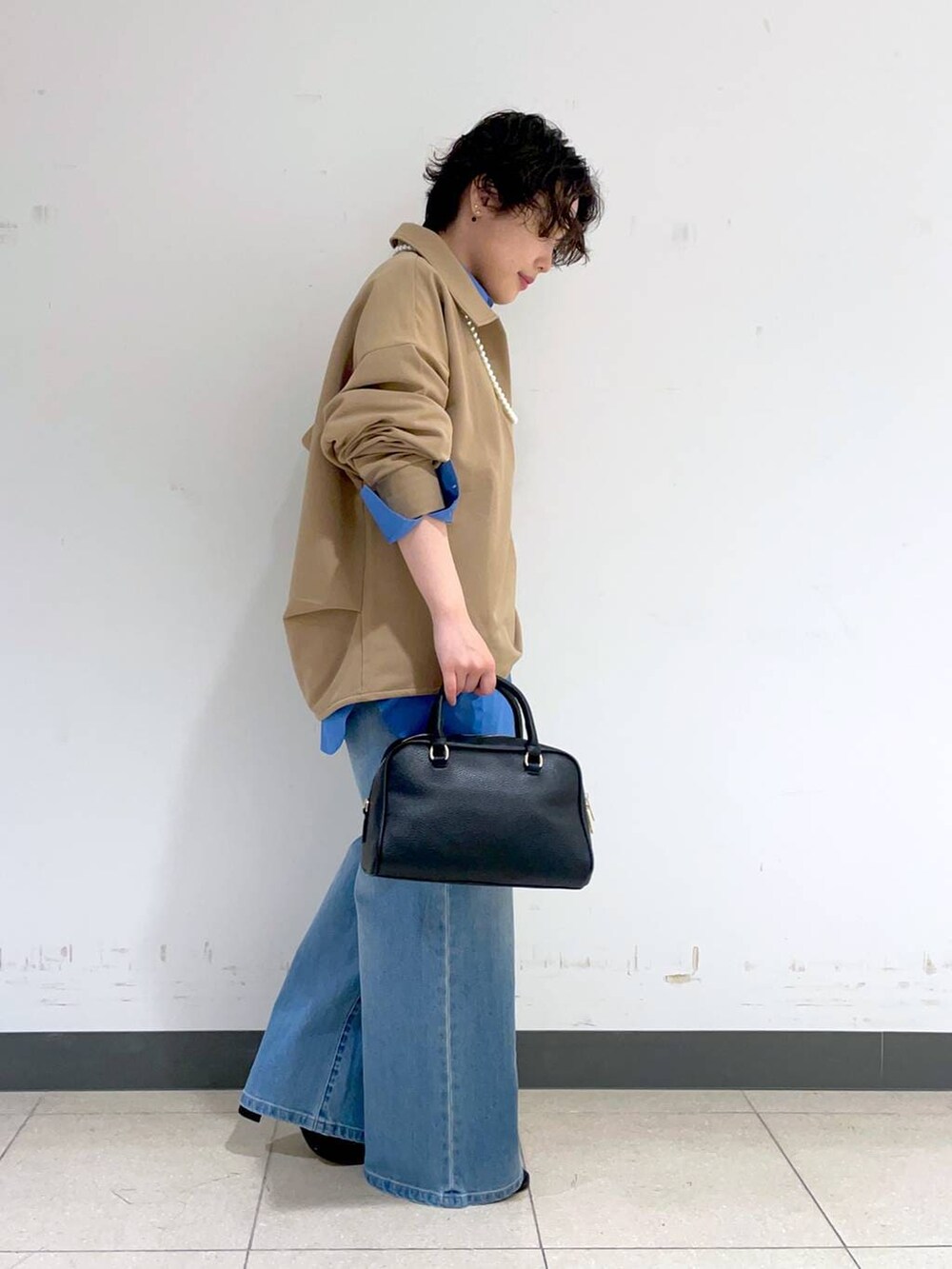 ブルー系のデニムパンツ、ブラック系のボストンバッグ、ブラック系のブーツを着用したレディースの秋コーディネートの2枚目の写真