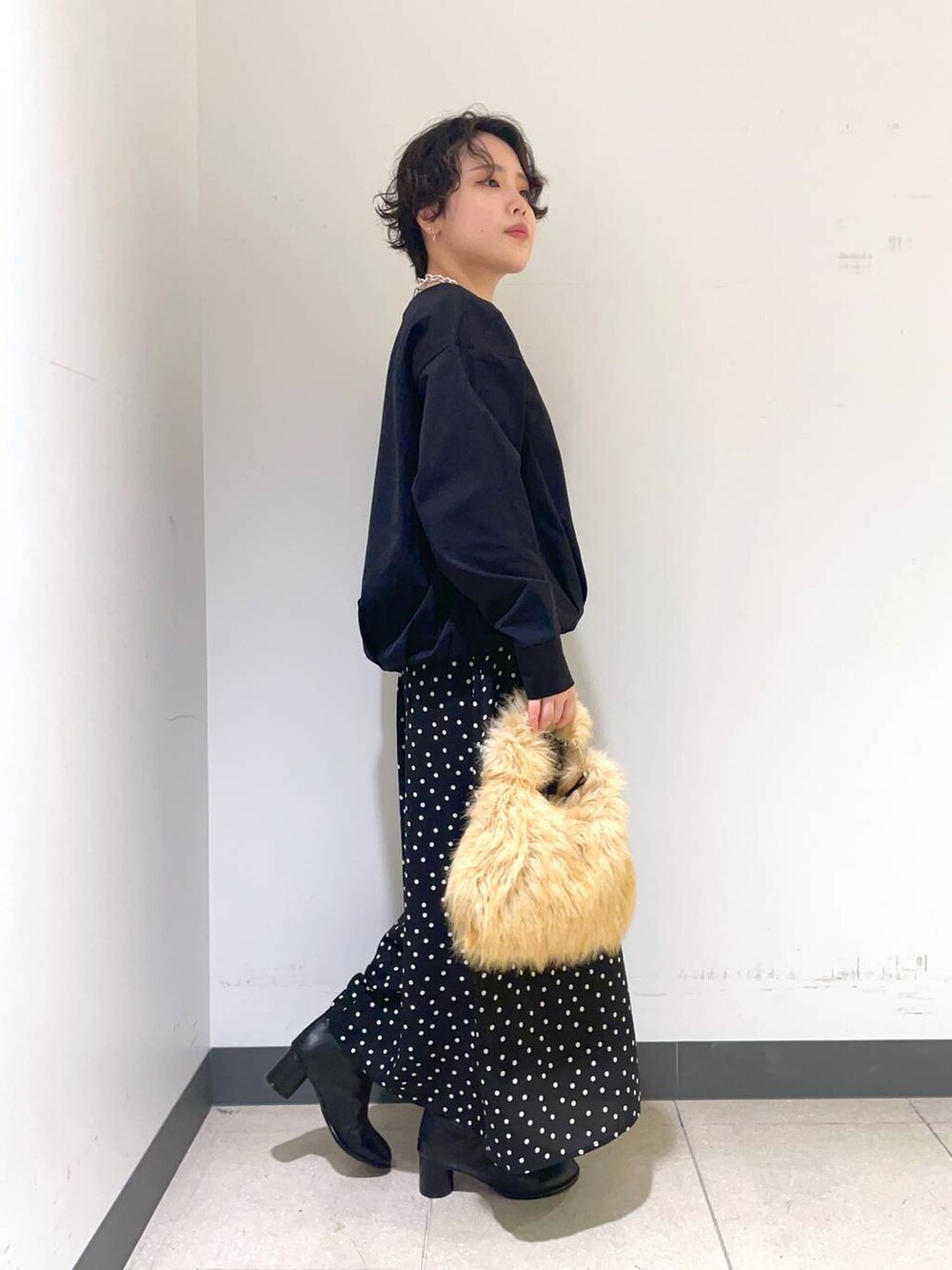 ベージュ系のトートバッグ、ブラック系のブーツ、その他のスカートを着用したレディースの秋コーディネートの2枚目の写真