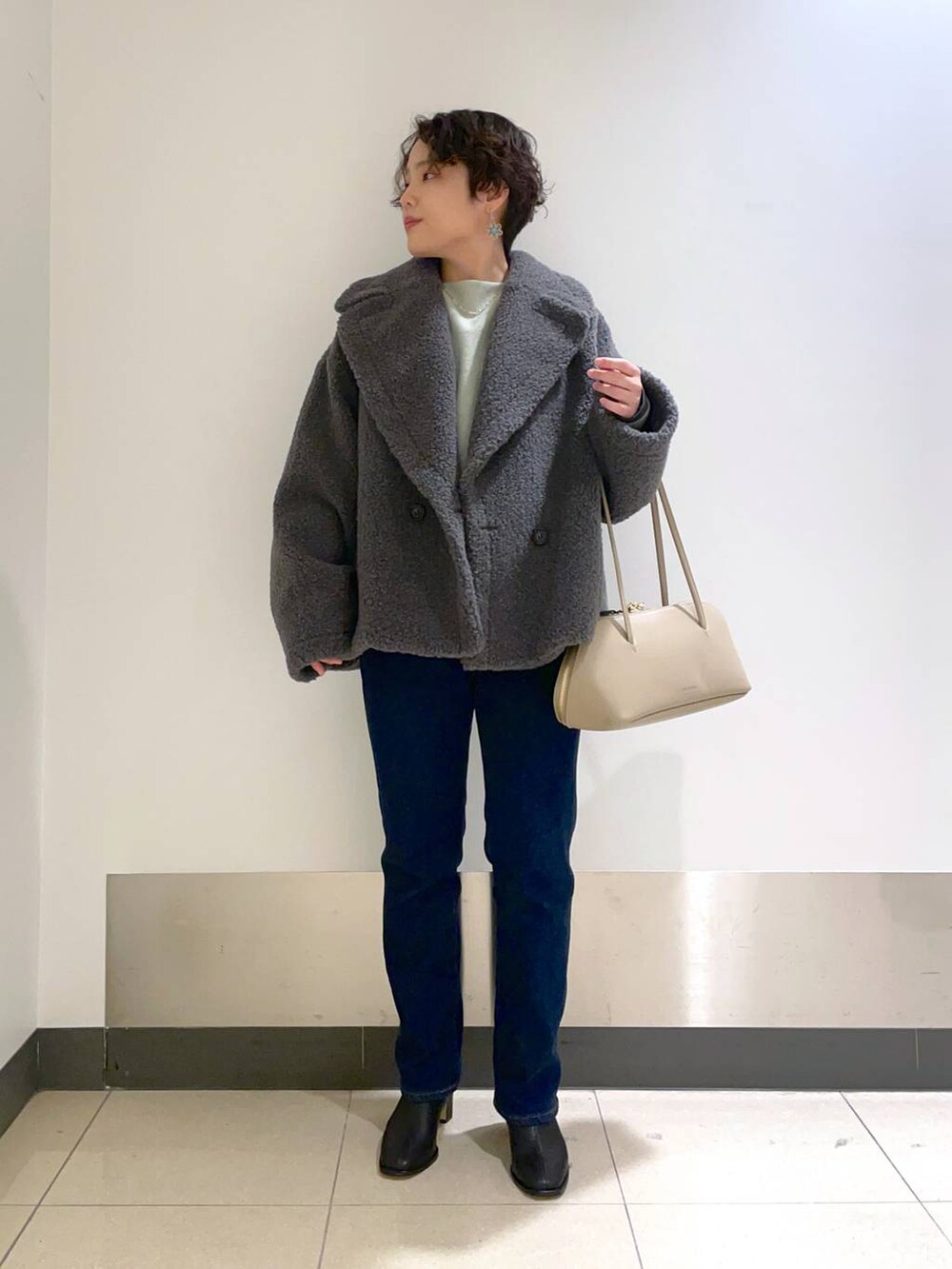 ベージュ系のトートバッグ、グリーン系のニット/セーター、グレー系のピーコートを着用したレディースの秋コーディネートの3枚目の写真