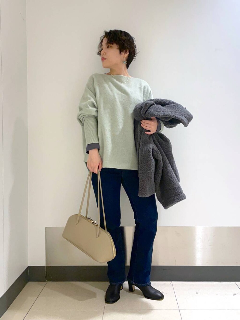 ベージュ系のトートバッグ、グリーン系のニット/セーター、グレー系のピーコートを着用したレディースの秋コーディネートの2枚目の写真