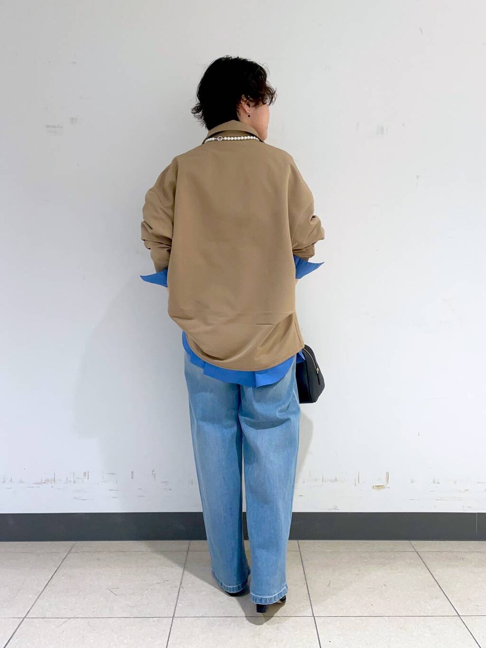 ブルー系のデニムパンツ、ブラック系のボストンバッグ、ブラック系のブーツを着用したレディースの秋コーディネートの3枚目の写真