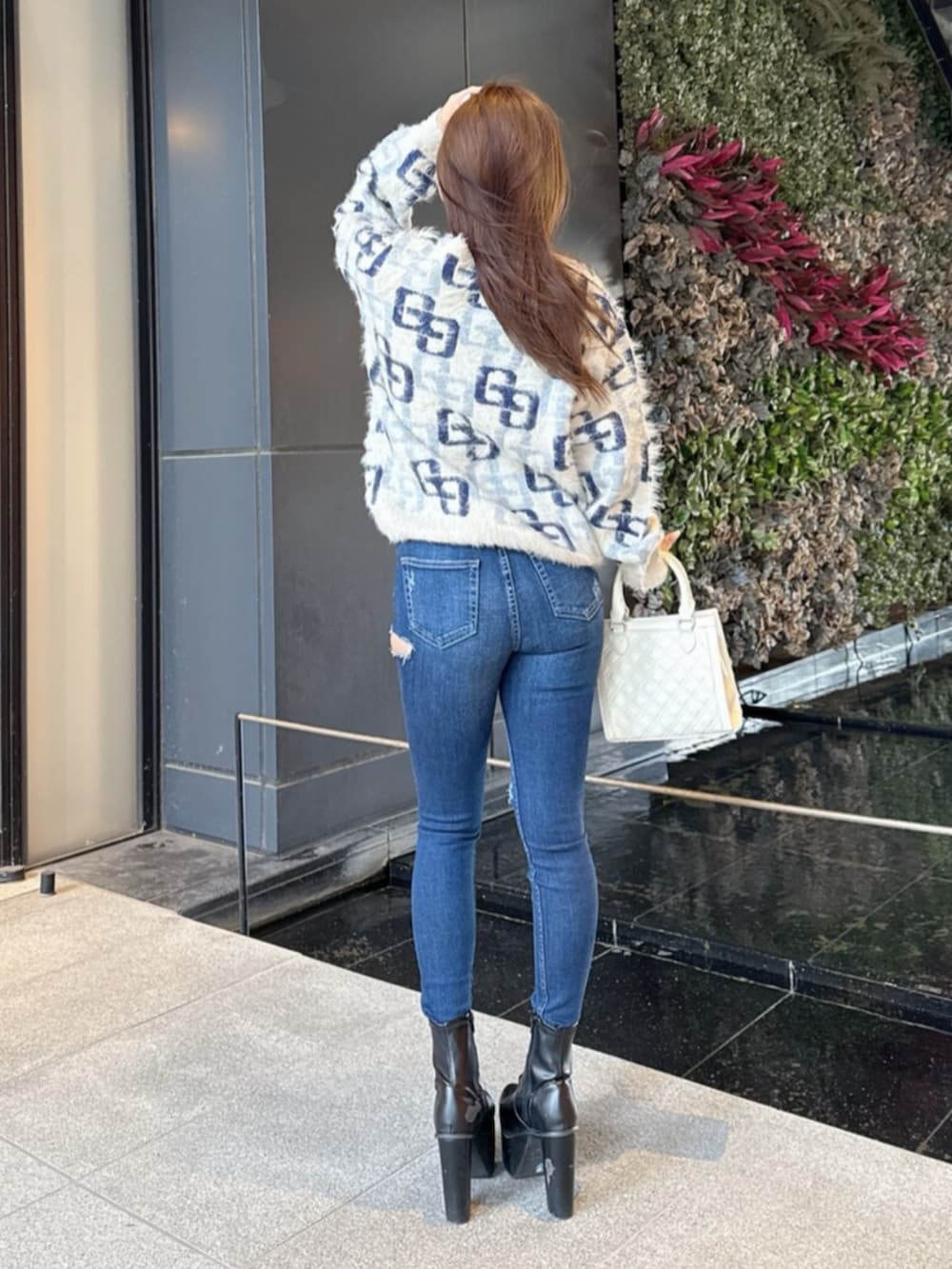 ブラック系のブーツ、ホワイト系のニット/セーター、ブルー系のデニムパンツを着用したレディースの冬コーディネートの3枚目の写真