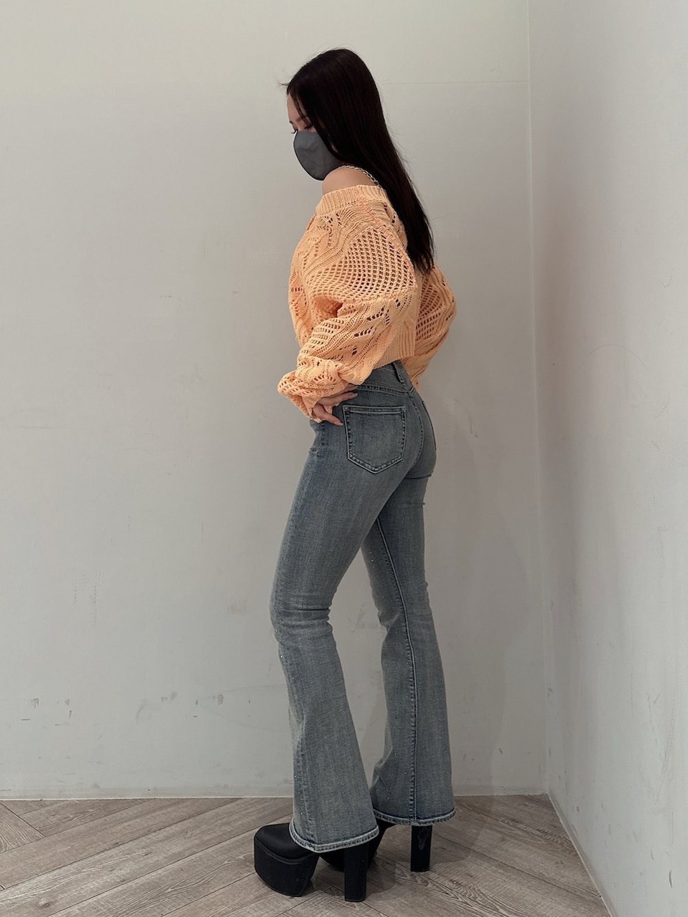 オレンジ系のニット/セーター、ホワイト系のキャミソール、ブルー系のデニムパンツを着用したレディースの春コーディネートの2枚目の写真