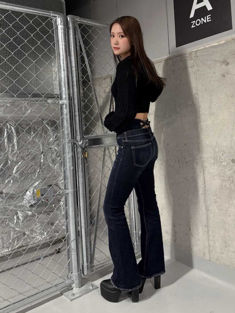 ブラック系のブーツ、ブラック系のニット/セーター、ブルー系のデニムパンツを着用したレディースの冬コーディネートの2枚目の写真