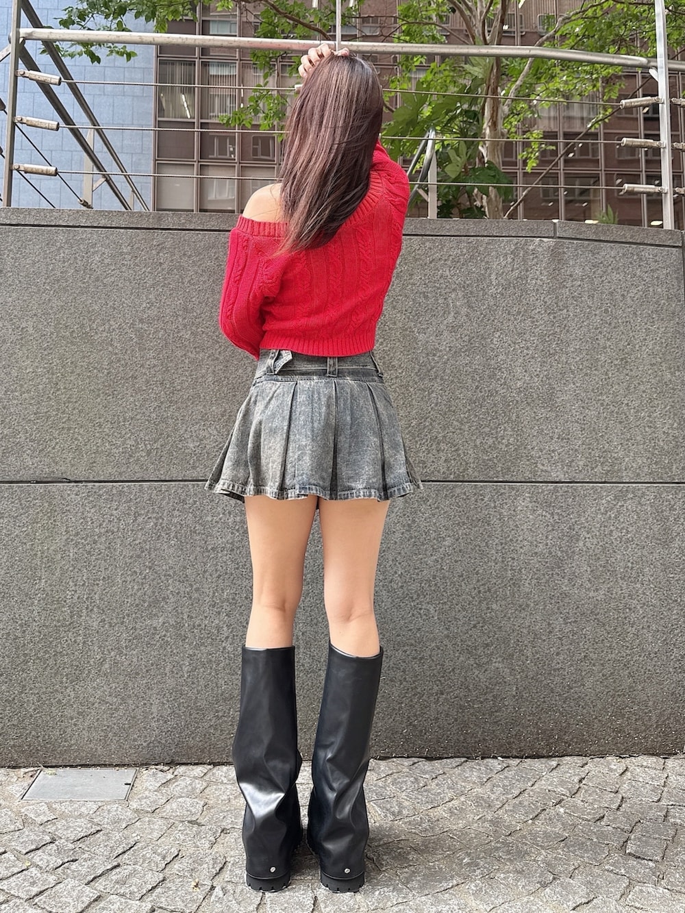 レッド系のニット/セーター、ブルー系のデニムスカート、ブラック系のブーツを着用したレディースの秋コーディネートの3枚目の写真