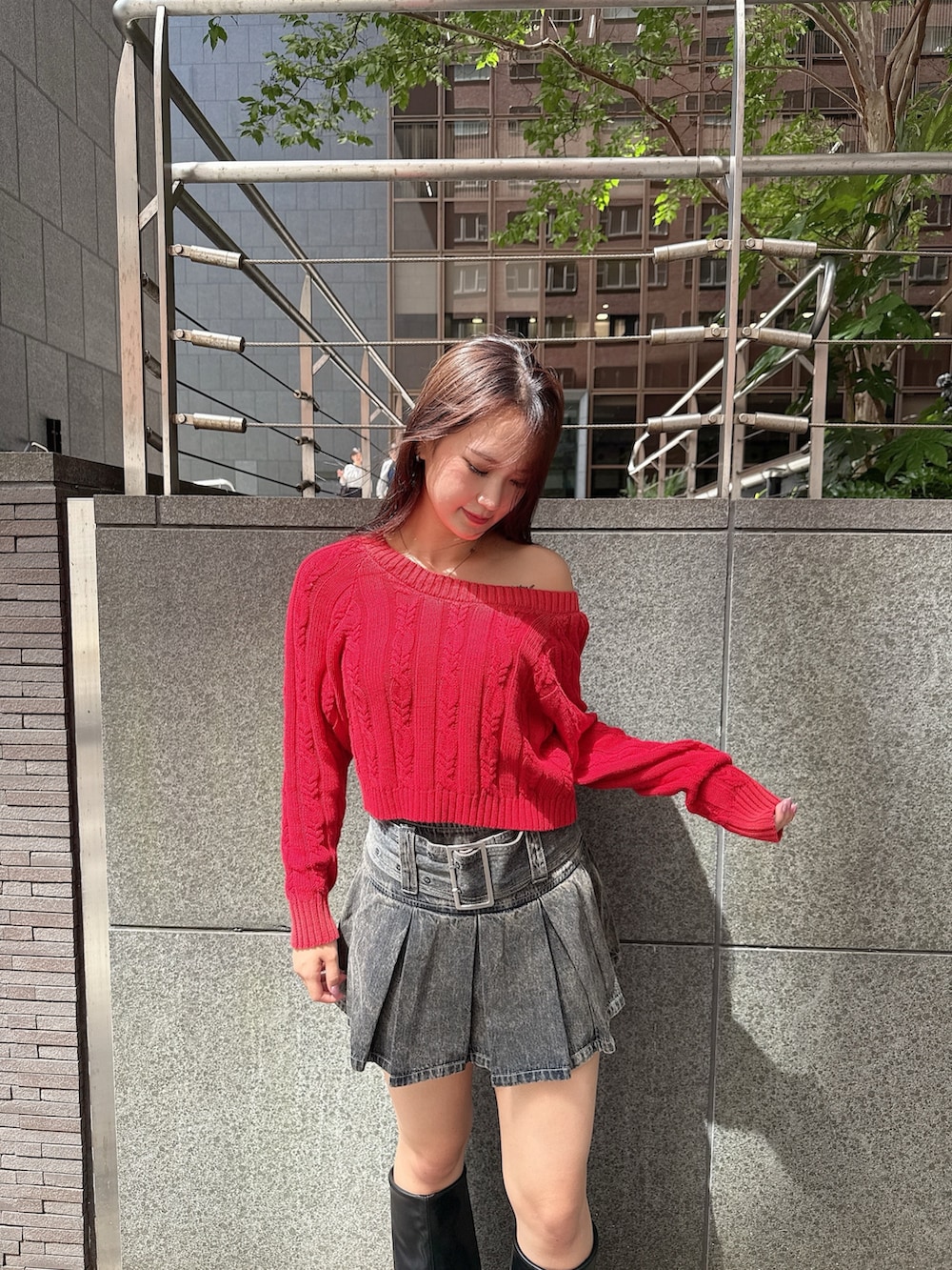 レッド系のニット/セーター、ブルー系のデニムスカート、ブラック系のブーツを着用したレディースの秋コーディネートの4枚目の写真