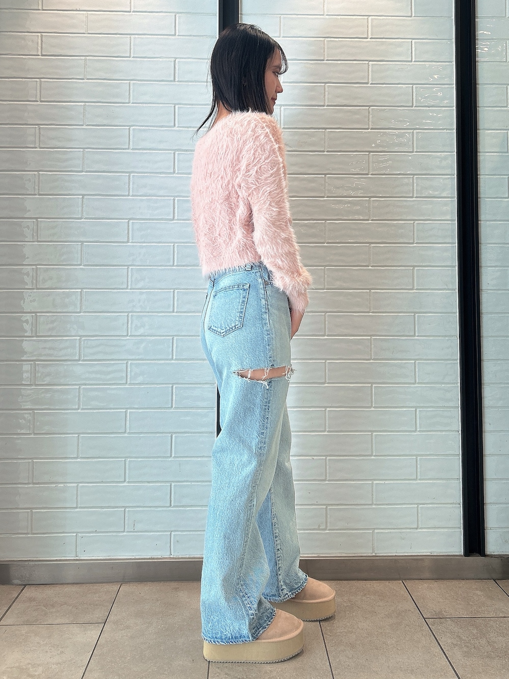 ピンク系のニット/セーター、ブルー系のデニムパンツ、ベージュ系のブーツを着用したレディースの冬コーディネートの2枚目の写真