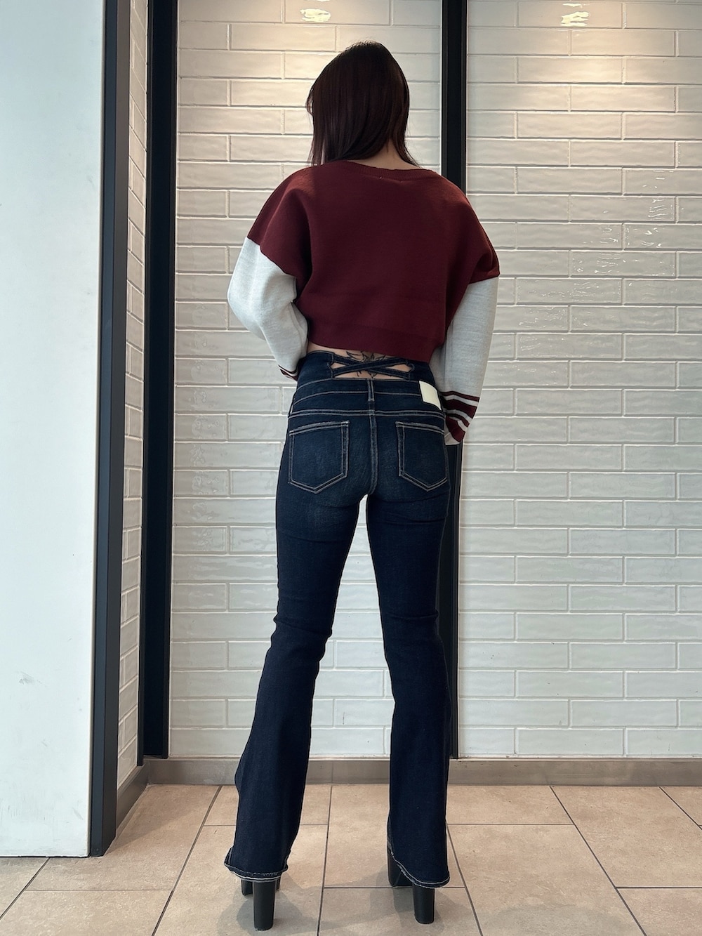 ブルー系のデニムパンツ、レッド系のニット/セーター、ブラック系のブーツを着用したレディースの秋コーディネートの4枚目の写真