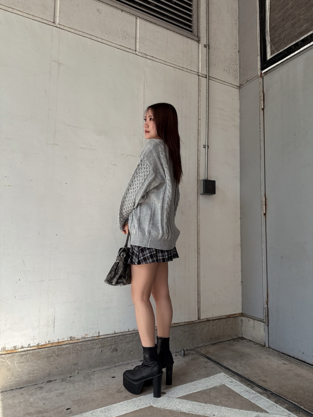 グレー系のニット/セーター、ブラック系のスカート、ブラック系のハンドバッグを着用したレディースの秋コーディネートの2枚目の写真