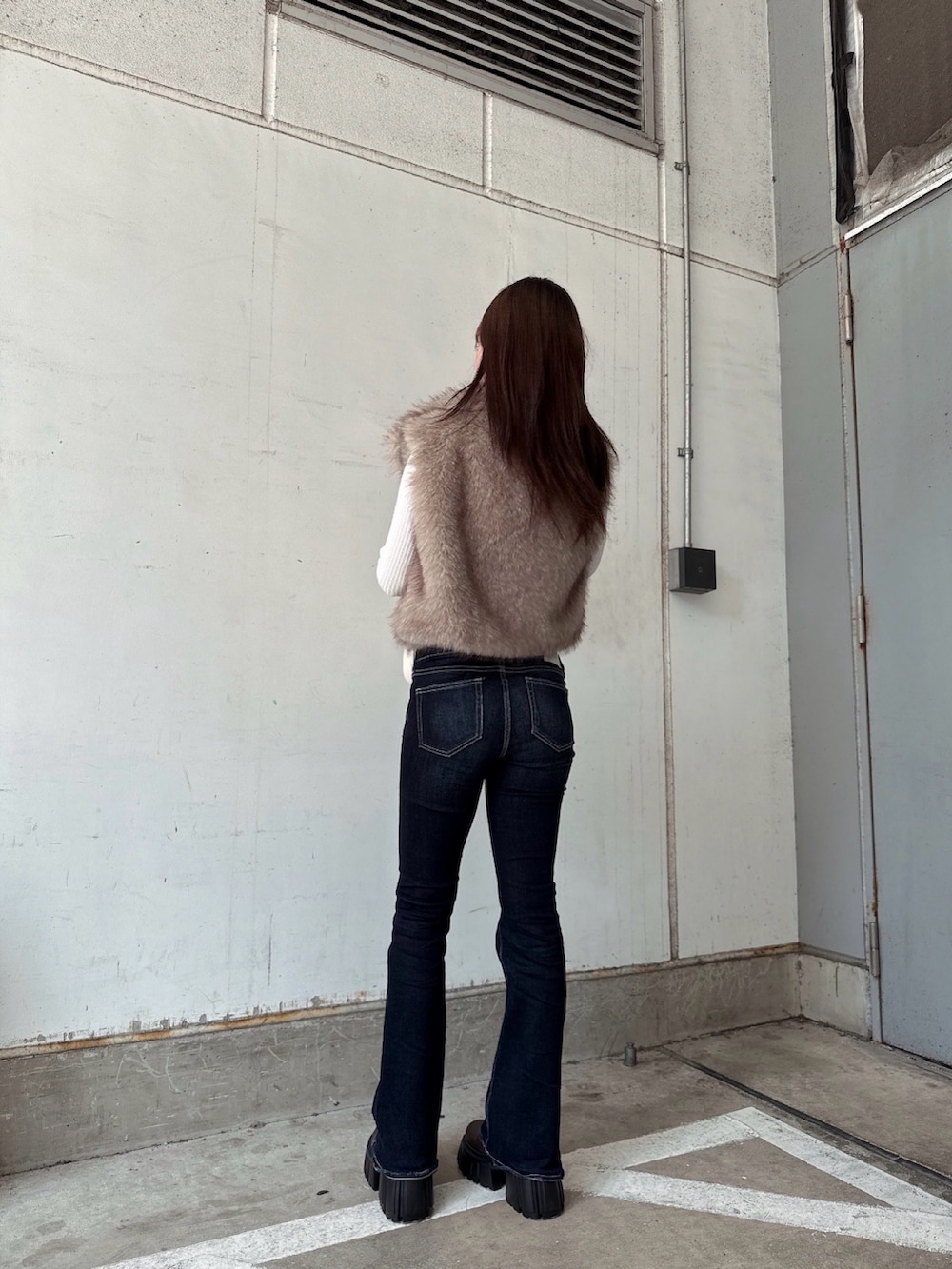 ホワイト系のニット/セーター、ホワイト系のベスト、ブルー系のデニムパンツを着用したレディースの秋コーディネートの3枚目の写真