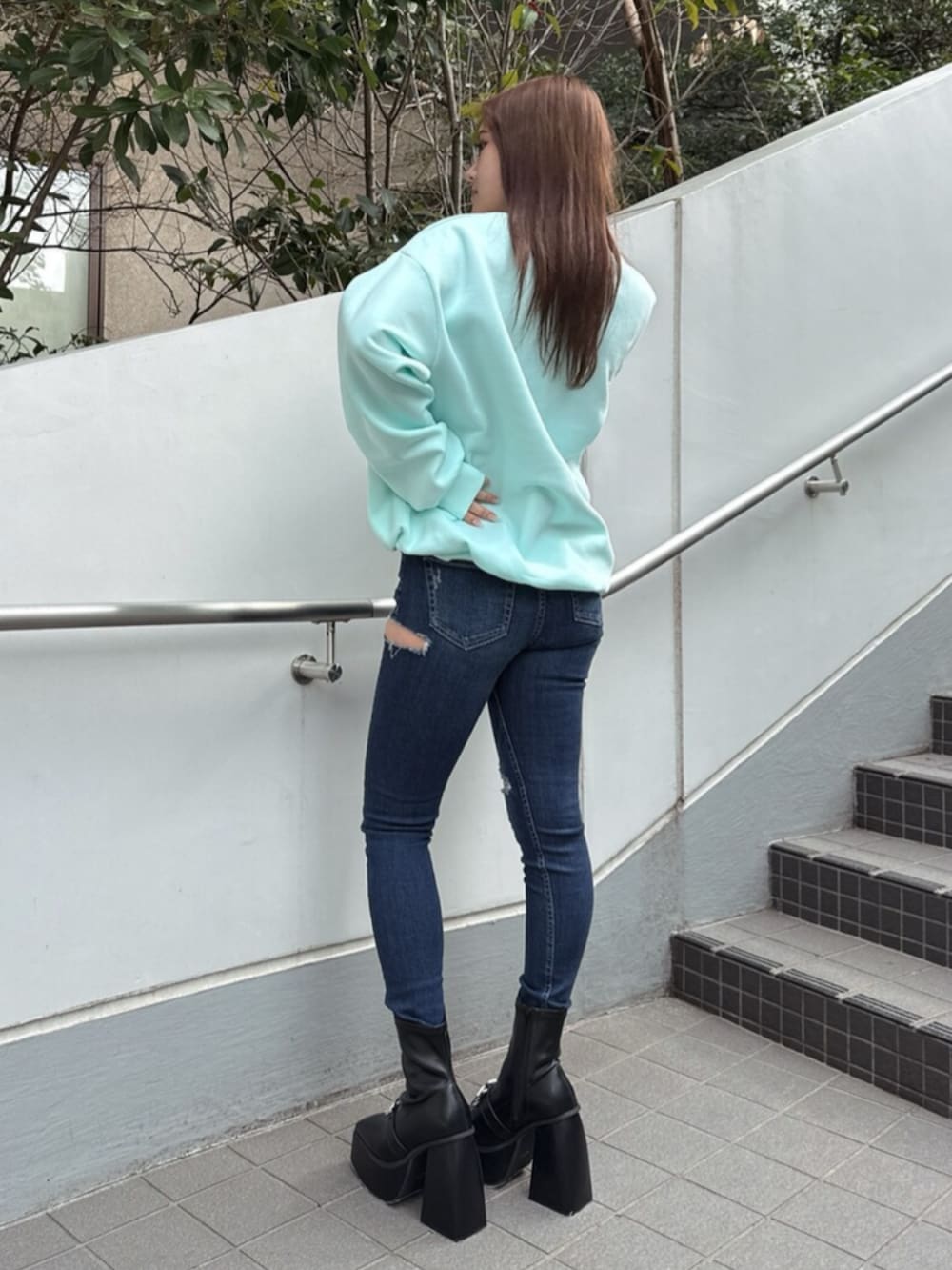 ブルー系のデニムパンツ、ホワイト系のショルダーバッグ、グリーン系のスウェットを着用したレディースの冬コーディネートの2枚目の写真