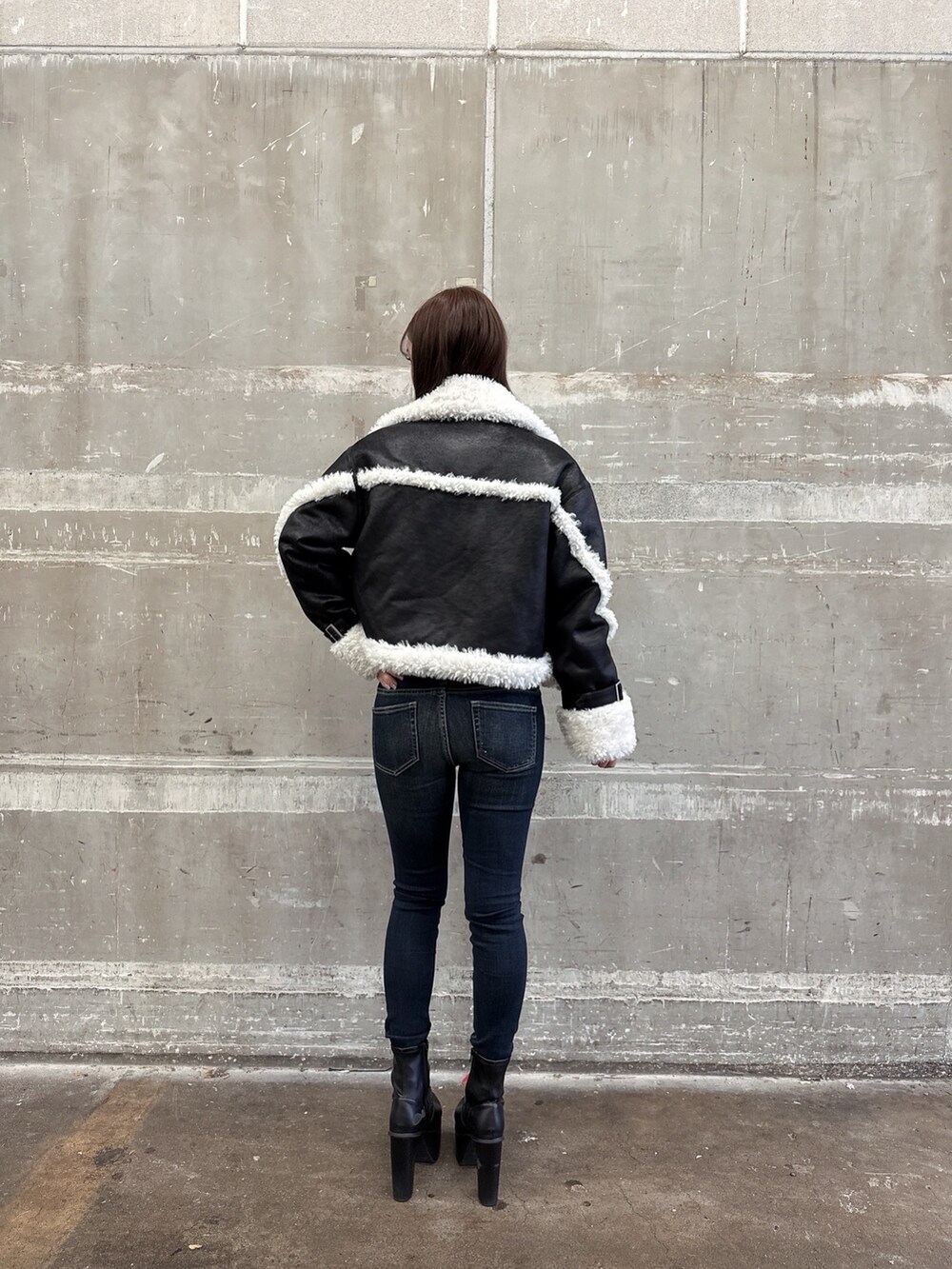 ブラック系のムートンコート、ブラック系のスウェット、ブルー系のデニムパンツを着用したレディースの秋コーディネートの3枚目の写真