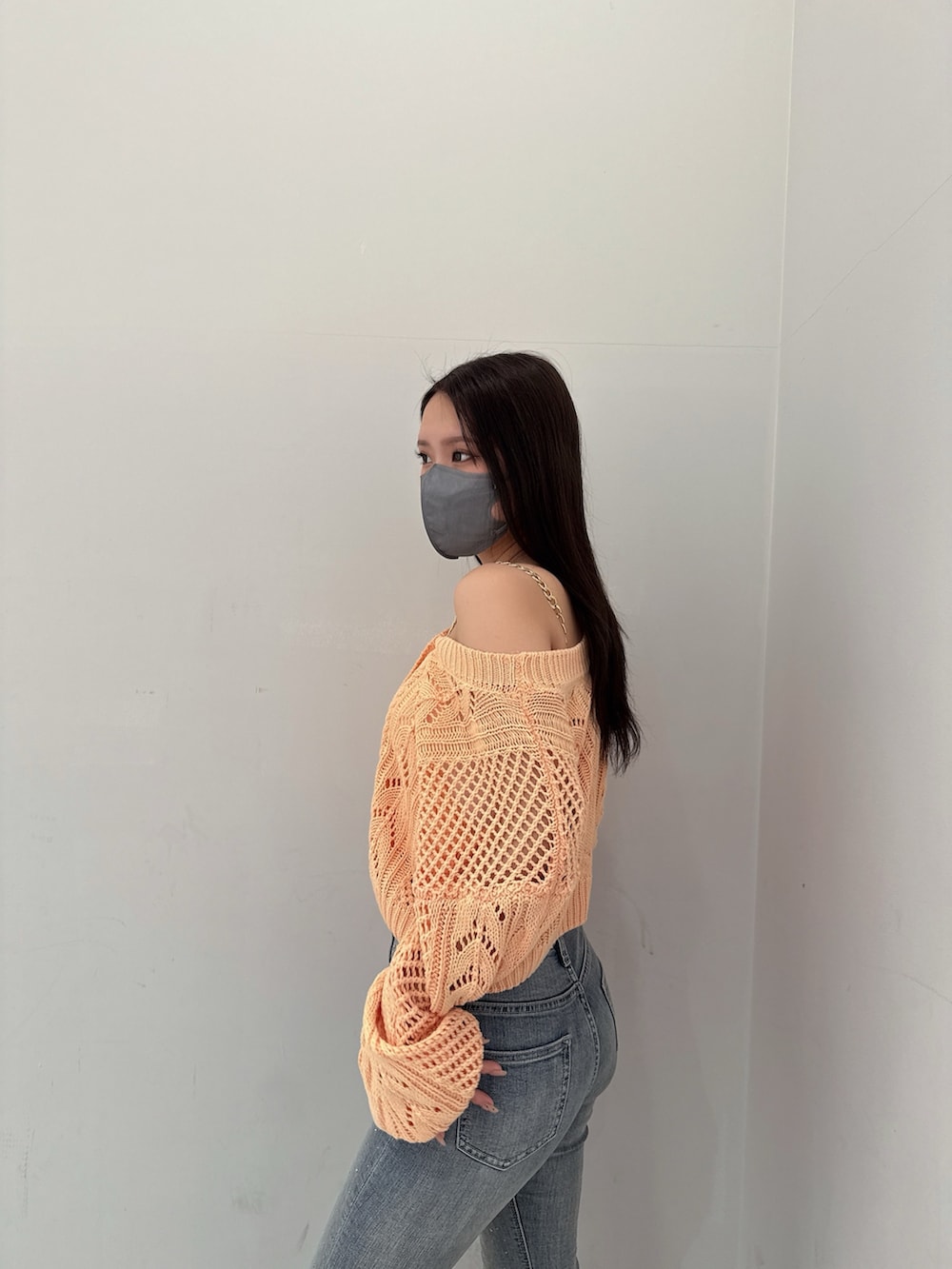 オレンジ系のニット/セーター、ホワイト系のキャミソール、ブルー系のデニムパンツを着用したレディースの春コーディネートの5枚目の写真