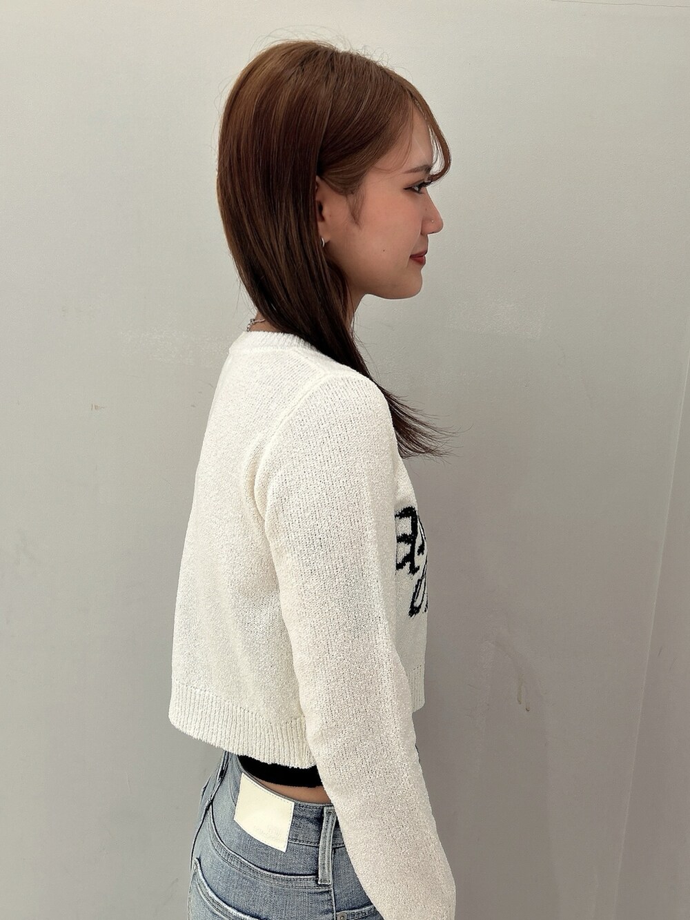 ホワイト系のカーディガン/ボレロ、ブラック系のキャミソール、ブルー系のデニムパンツを着用したレディースの春コーディネートの5枚目の写真