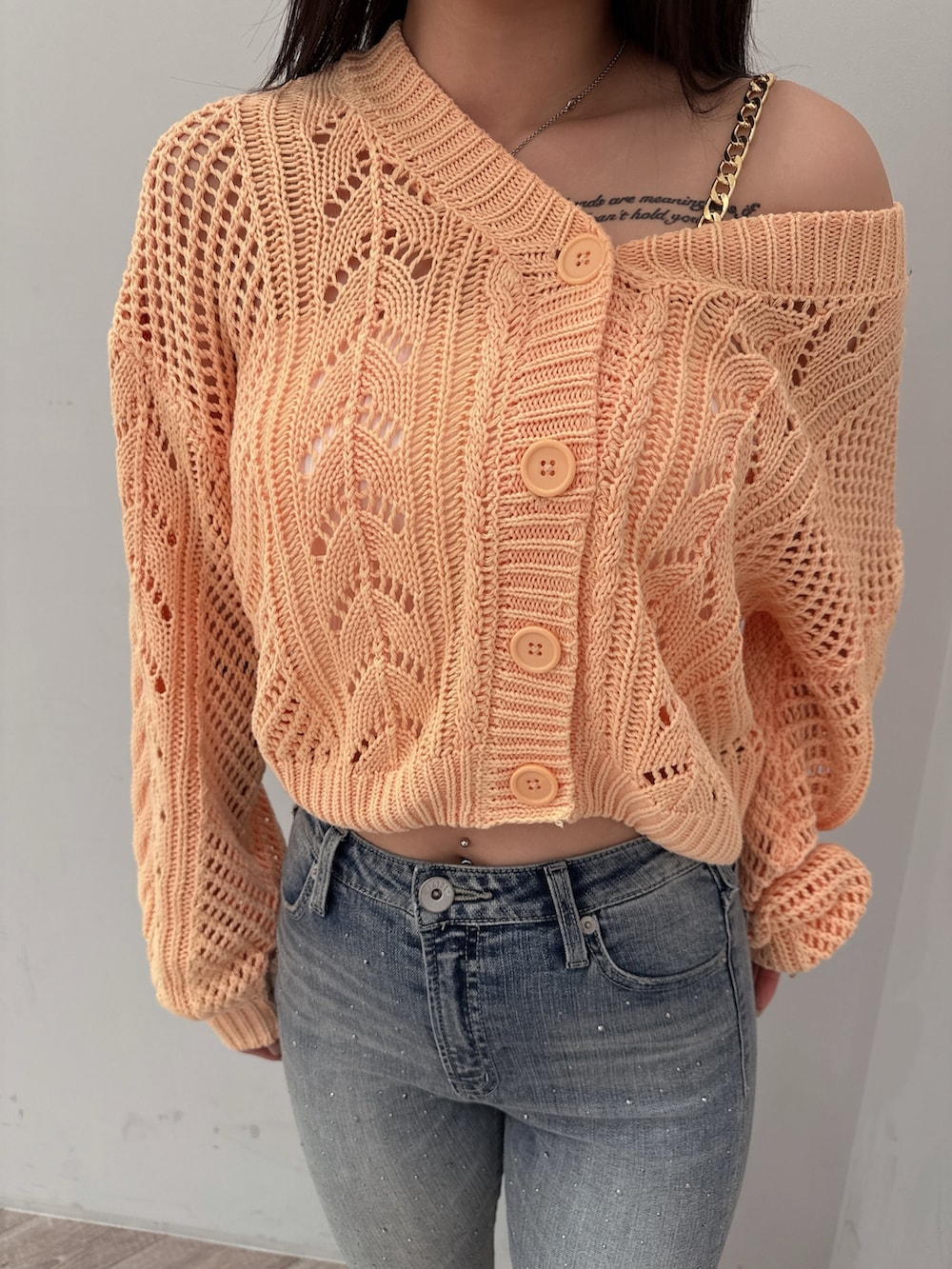 オレンジ系のニット/セーター、ホワイト系のキャミソール、ブルー系のデニムパンツを着用したレディースの春コーディネートの7枚目の写真