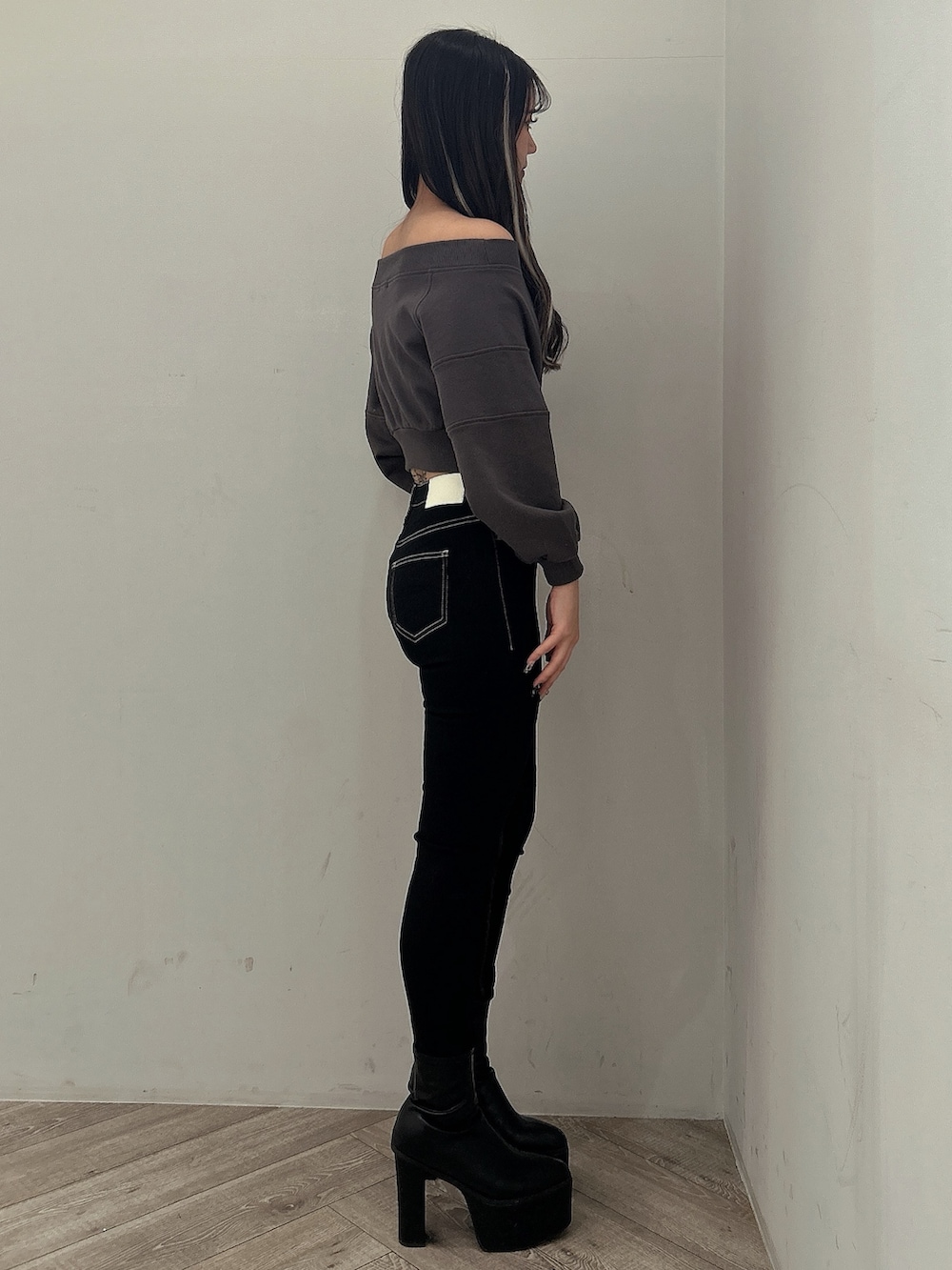 グレー系のスウェット、ブラック系のデニムパンツ、ブラック系のブーツを着用したレディースの冬コーディネートの2枚目の写真