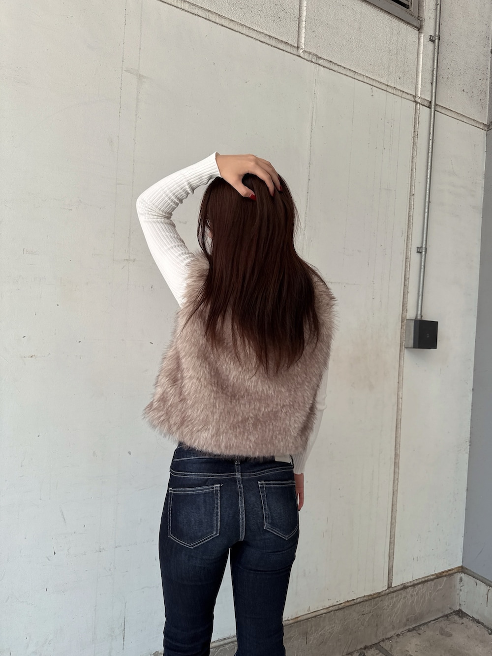 ホワイト系のニット/セーター、ホワイト系のベスト、ブルー系のデニムパンツを着用したレディースの秋コーディネートの6枚目の写真