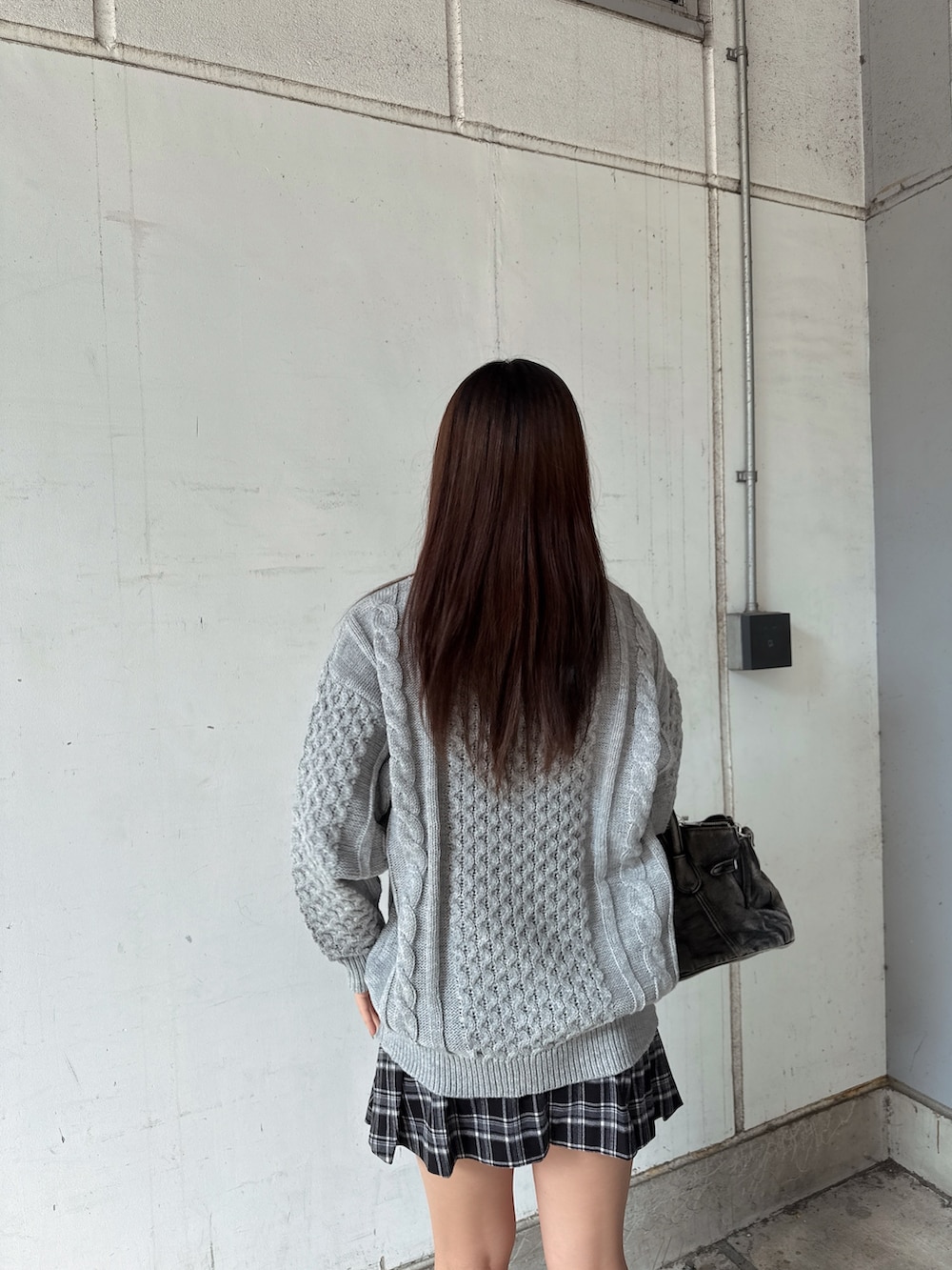 グレー系のニット/セーター、ブラック系のスカート、ブラック系のハンドバッグを着用したレディースの秋コーディネートの6枚目の写真