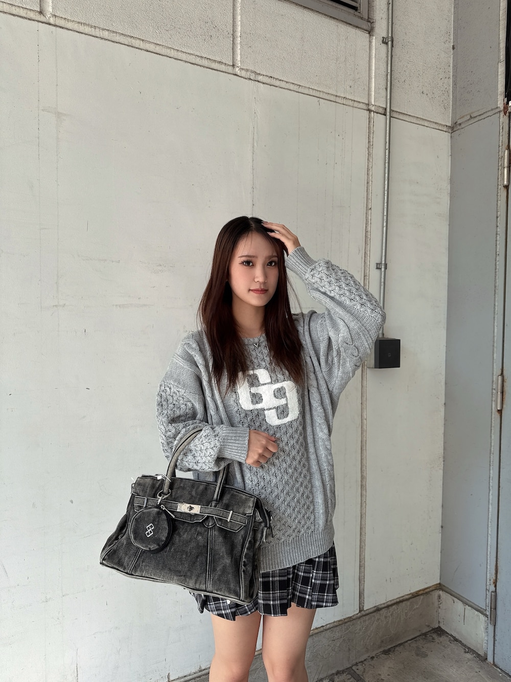 グレー系のニット/セーター、ブラック系のスカート、ブラック系のハンドバッグを着用したレディースの秋コーディネートの4枚目の写真