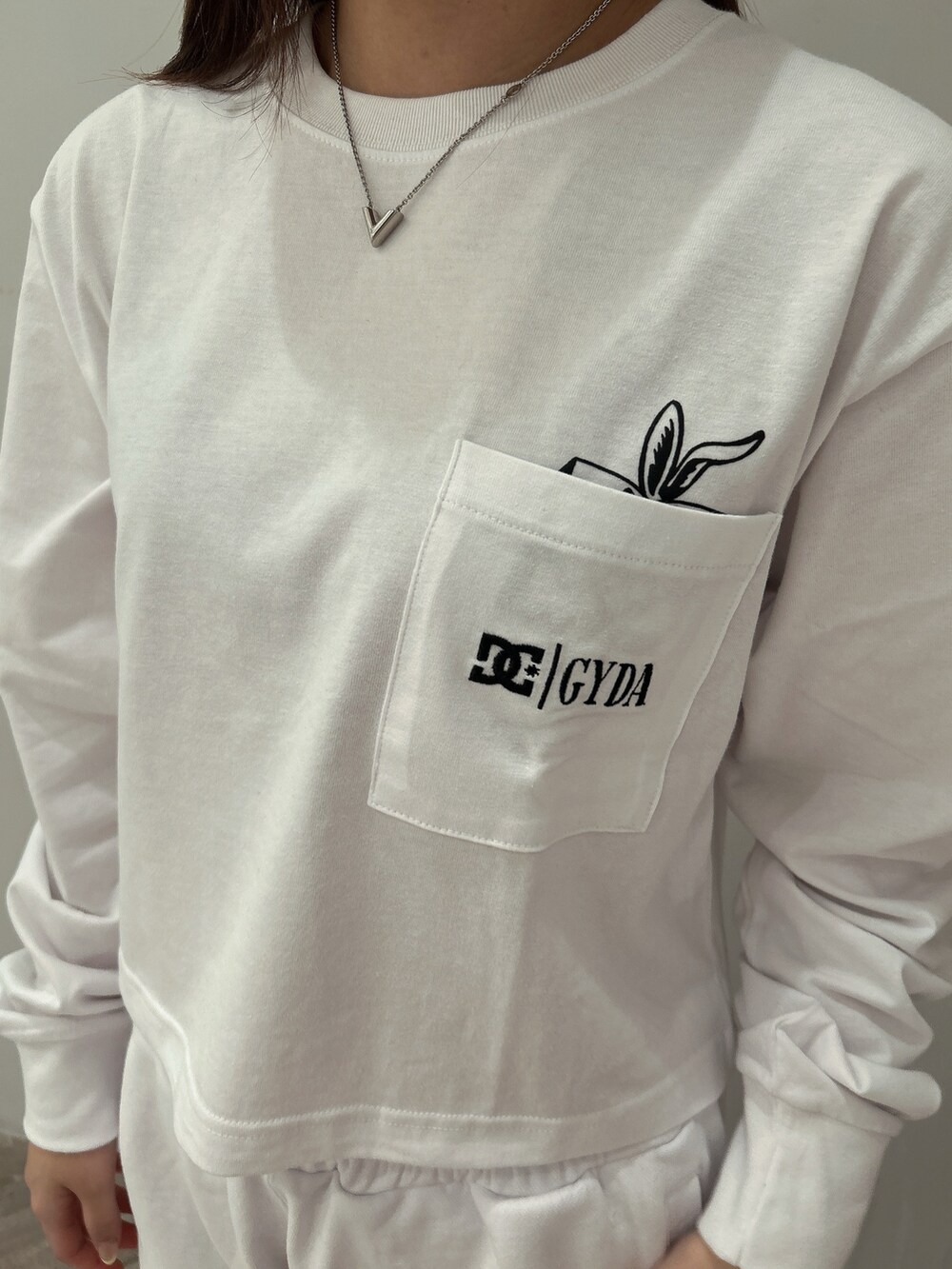 ホワイト系のTシャツ/カットソー、ホワイト系のスウェットパンツ、ブラック系のパンプスを着用したレディースの春コーディネートの5枚目の写真