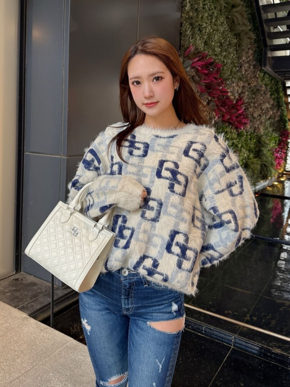 ブラック系のブーツ、ホワイト系のニット/セーター、ブルー系のデニムパンツを着用したレディースの冬コーディネートの4枚目の写真